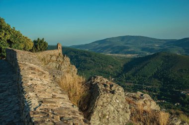 Küçük gözetleme kulesi ve dağlık arazi ile uçurum üzerinde taş duvar