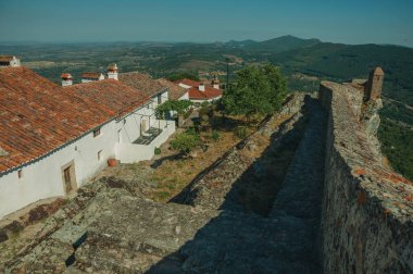 Sırt ve tepelik manzara üzerinde eski evler ve taş duvar