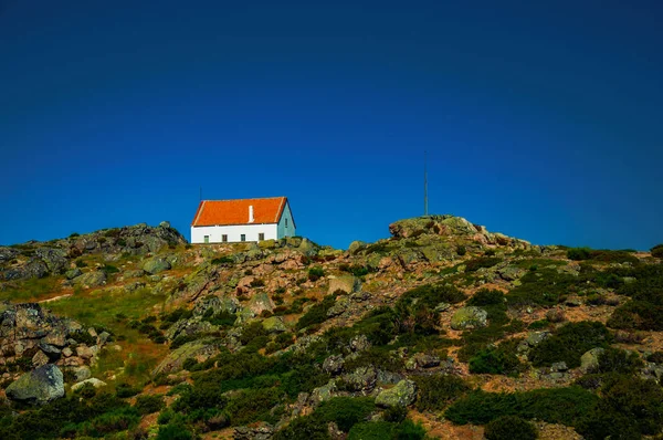 Haus auf Hügellandschaft mit Büschen und Felsen — Stockfoto