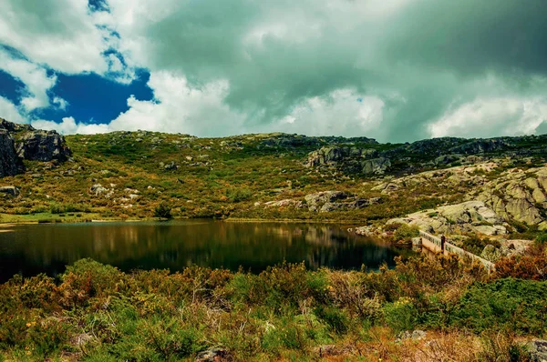 Dam lake among rocks and bushes on highlands — Stock Photo, Image