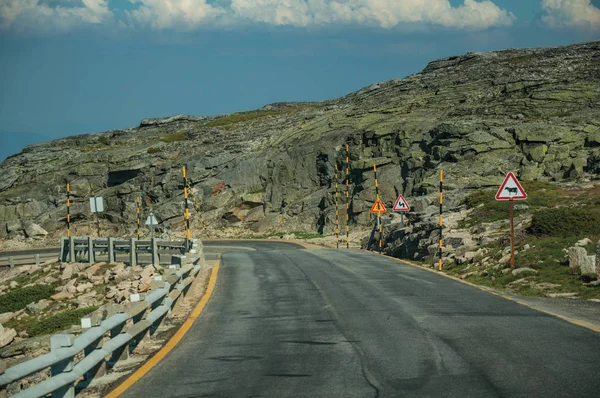 Route sur un paysage vallonné recouvert de rochers et de buissons — Photo