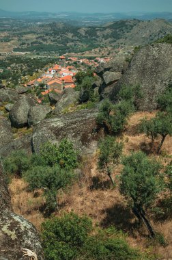 Monsanto'da ağaçlar ve kayalarla kaplı engebeli manzara