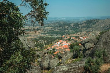Monsanto'da ağaçlar ve kayalarla kaplı engebeli manzara