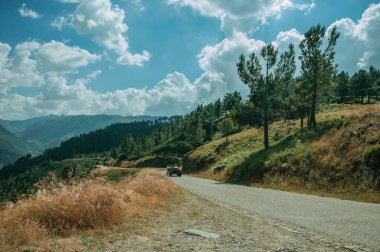 Engebeli arazide karayolundan geçen traktör