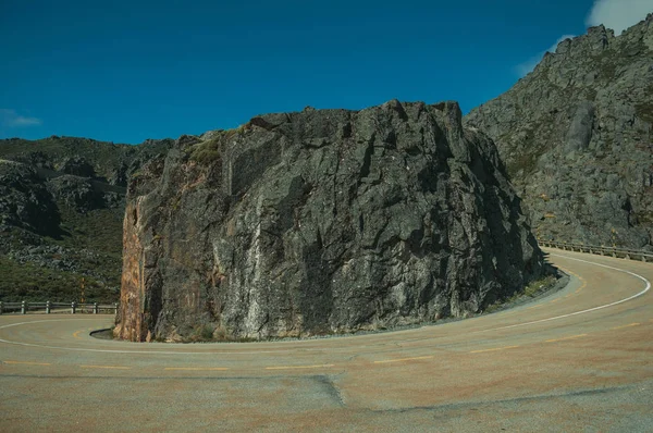 Vägbanan går runt en klippa på kuperat landskap — Stockfoto