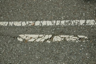 Küçük çakıl takılı asfalt ve yıpranmış bir sokak şeridi