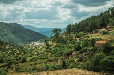 Rustik evler ile kayalar ve ağaçlar la kaplı tepelik manzara
