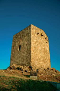 Gün batımında kayalık tepe üzerinde taş kare kule