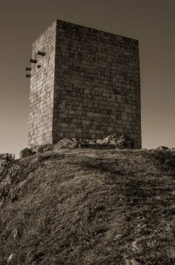 Gün batımında kayalık tepe üzerinde taş kare kule