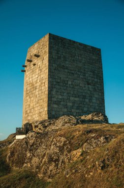 Gün batımında kayalık tepe üzerinde taş kare kule