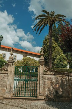 Eski bina ve yeşil ağaçların önünde demir kapı