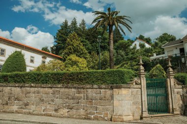 Eski bina ve yeşil ağaçların önünde demir kapı