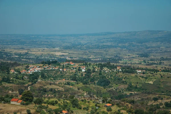 Countryside landscape with trees and cottage roofs