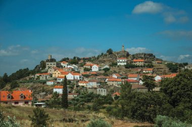 Üstünde küçük bir köyün evleri ile tepelik manzara