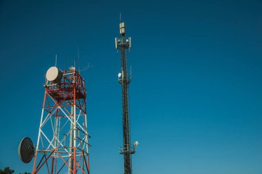 Antenli ve mavi gökyüzüne sahip telekomünikasyon kuleleri