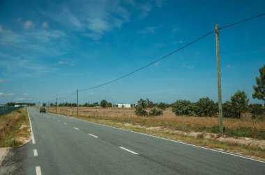 Elektrik direkleri ile kırsal yoldan geçen araba