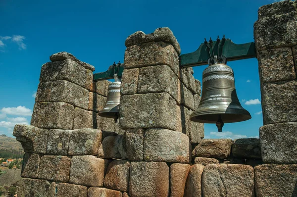 Primer plano de campanas de bronce en la parte superior de la pared de ladrillo de piedra — Foto de Stock