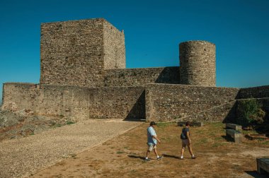 Marvao Kalesi'nde duvarların ve kulelerin önünde yürüyen insanlar