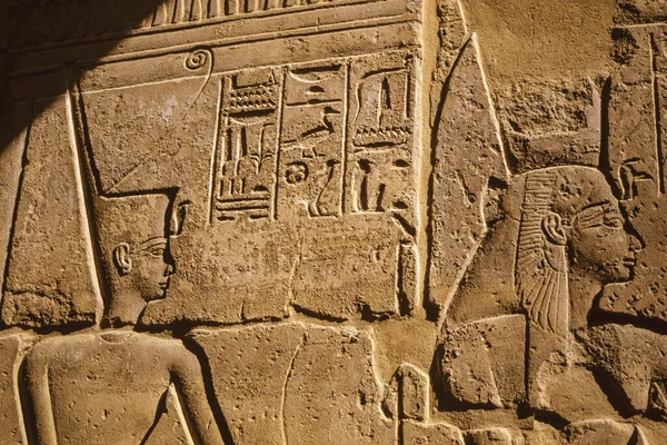 Wall with hieroglyphs depicting the head of pharaoh and his queen carved in low relief by ancient Egyptians, in a temple on southern Egypt. — Stock Image Wall Hieroglyphs Depicting Head Pharaoh His Queen Carved Low Relief Royalty Free Stock Photos