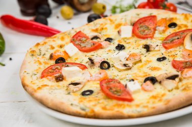 Pizza domates, peynir ve deniz ürünleri Beyaz ahşap zemin üzerinde. Sebze ile dekore edilmiş arka plan.