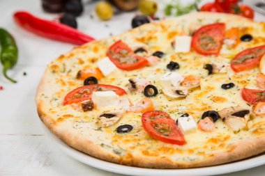 Pizza domates, peynir ve deniz ürünleri Beyaz ahşap zemin üzerinde. Sebze ile dekore edilmiş arka plan.