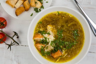 soğan çorbası ile kraker Beyaz ahşap zemin üzerinde beyaz bir tabak içinde. Arka plan sebze ile süslüdür.