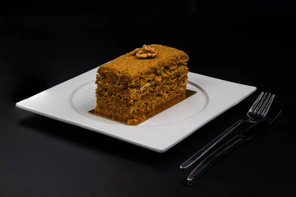 honey cake on a white plate on a black background