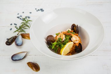 Yanında çatal ve kaşıkla, bir kadeh beyaz şarap ve metin için bir yer deniz mavisi dokular üzerinde bir deniz ürünleri risotto genel gider bir fotoğrafı