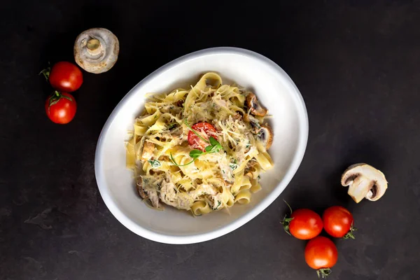 Mantar ve kızarmış tavuk jambon krem peynir soslu makarna fettuccine. Belgili tanımlık siyah geçmiş sebze ve bir kesme tahtası ile süslüdür