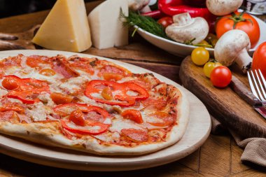 ahşap bir tahta üzerinde salam pizza, ahşap arka plan sebze ve çatal ile dekore