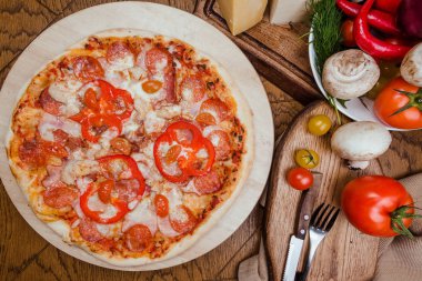 ahşap bir tahta üzerinde salam pizza, ahşap arka plan sebze ve çatal ile dekore