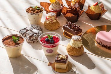 Beyaz bir tahtada doğal ışık altında çeşitli tatlılar.