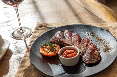 Orta pişmiş biftek, siyah bir tabakta, içinde doğal ışık var.