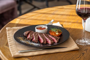 Orta pişmiş biftek, siyah bir tabakta, içinde doğal ışık var.