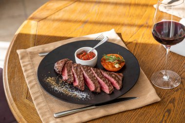 Orta pişmiş biftek, siyah bir tabakta, içinde doğal ışık var.