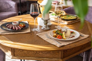 Yemek ve içeceklerle kaplı bir masa. Biftek, sebzeli ızgara kalamar, dereotlu omlet, maydanoz ve sebze..