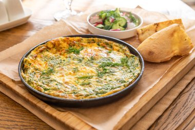 Maydanoz ve dereotlu tavada omlet. Taze ekmek ve taze sebzelerle servis yapın..