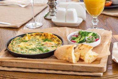 Maydanoz ve dereotlu tavada omlet. Taze ekmek ve taze sebzelerle servis yapın..