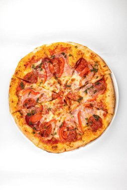 Beyaz tabakta jambonlu, sosisli ve domatesli pizza