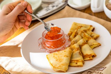 Geleneksel Rus yemeği. Kırmızı havyarlı gözleme ve kahve. Arkaplanda bir tablo seti.