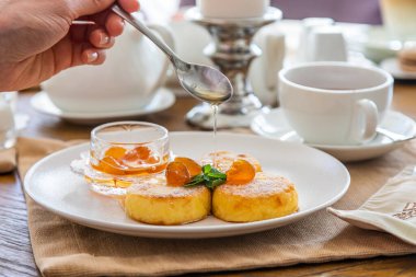 Peynirli kekler reçelle doldurulur. Reçelli cheesecake ile kahvaltı. Arka planda bir fincan çay..