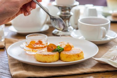 Peynirli kekler reçelle doldurulur. Reçelli cheesecake ile kahvaltı. Arka planda bir fincan çay..