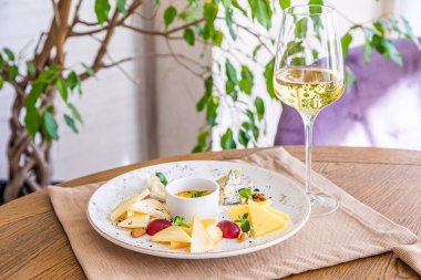 Peynir tabağı. Çeşitli peynirlerle dolu bir tabak. Atıştırmalıklar Peynirli bir bardak şarap..