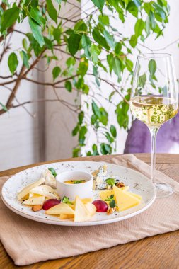 Peynir tabağı. Çeşitli peynirlerle dolu bir tabak. Atıştırmalıklar Peynirli bir bardak şarap..