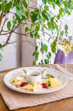 Peynir tabağı. Çeşitli peynirlerle dolu bir tabak. Atıştırmalıklar Peynirli bir bardak şarap..