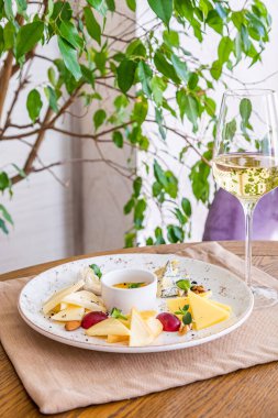 Peynir tabağı. Çeşitli peynirlerle dolu bir tabak. Atıştırmalıklar Peynirli bir bardak şarap..