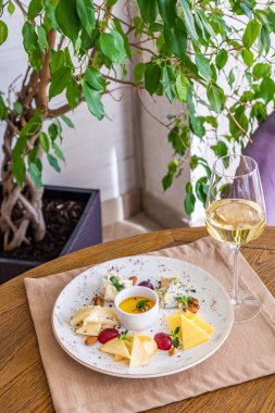 Peynir tabağı. Çeşitli peynirlerle dolu bir tabak. Atıştırmalıklar Peynirli bir bardak şarap..