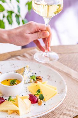 El bir bardak beyaz şarap alır. Peynir tabağı. Çeşitli peynirlerle dolu bir tabak. Atıştırmalıklar Peynirli bir bardak şarap..