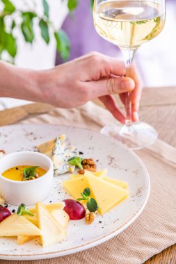 El bir bardak beyaz şarap alır. Peynir tabağı. Çeşitli peynirlerle dolu bir tabak. Atıştırmalıklar Peynirli bir bardak şarap..