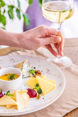 El bir bardak beyaz şarap alır. Peynir tabağı. Çeşitli peynirlerle dolu bir tabak. Atıştırmalıklar Peynirli bir bardak şarap..